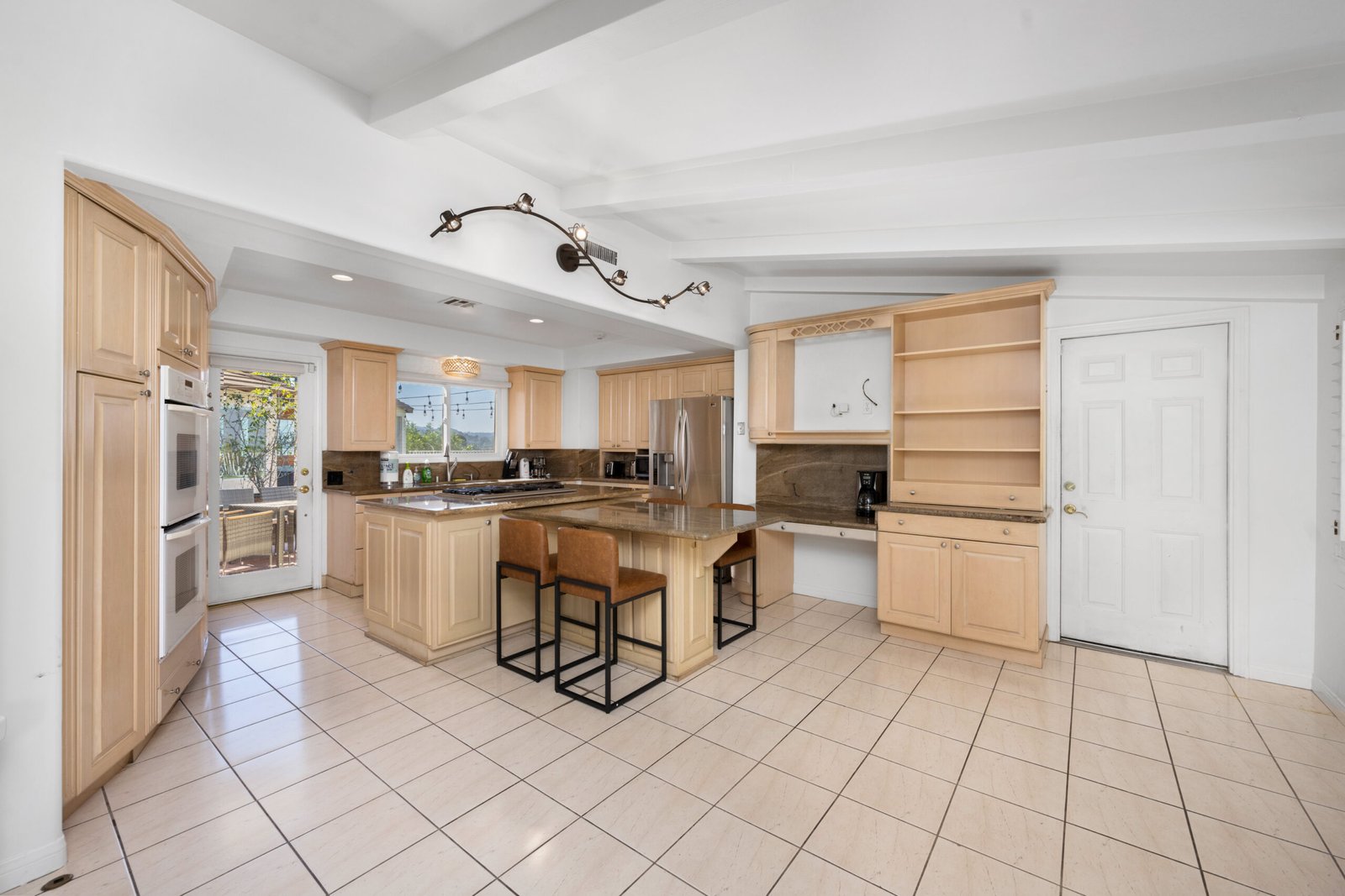A kitchen with wooden cabinets next to window blinds in Hidden Hills, CA