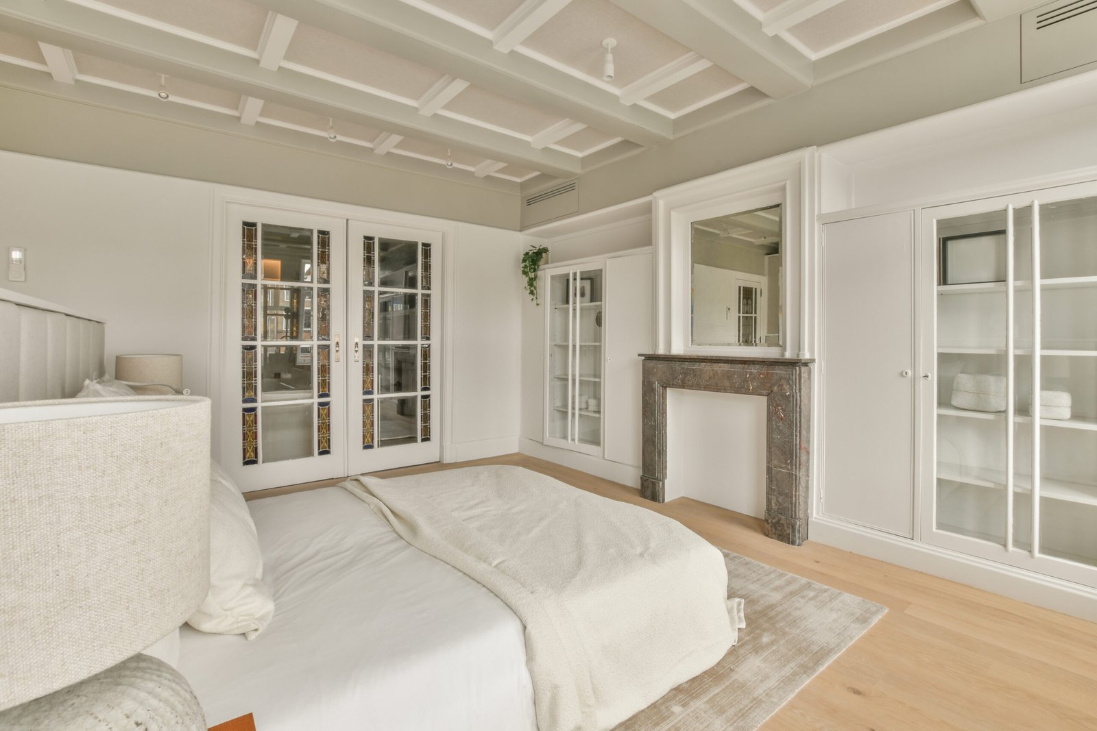 Spacious bright bedroom with a vintage bedside tables, white wardrobes and parquet floor